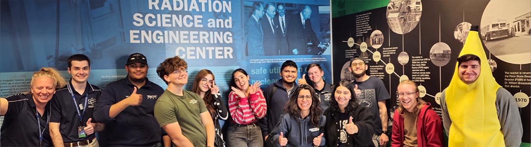 nine people stand in front of a classroom